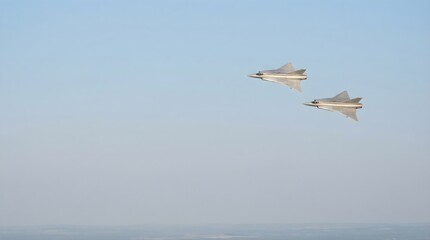 Fototapeta premium Two delta wing military fighter jets flying in formation high above landscape