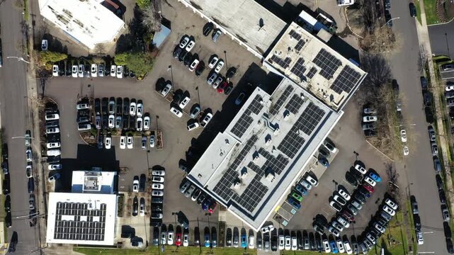 Aerial drone view of car dealership building in Beaverton Oregon USA with rooftop solar panels and full parking lot. Renewable energy, sustainable business and clean power infrastructure in 4K footage