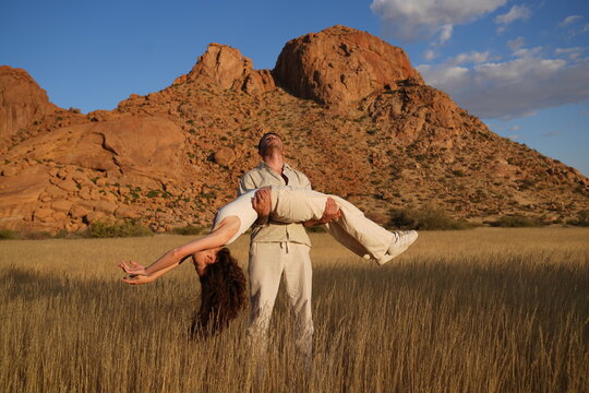 Young man carrying his girlfriend with a mountain backdrop
