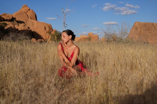 Young woman in red dress with dramatic mountain backdrop