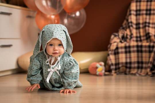 Baby in bunny hat crawling on the floor, celebrating first birthday