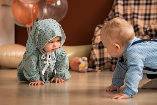 baby girl and boy crawling on floor during 1st birthday celebration.