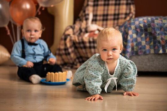 baby girl and boy crawling on floor during 1st birthday celebration.