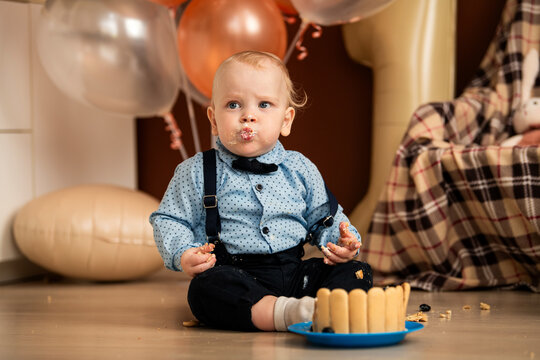 Baby boy celebrating first birthday with a messy cake smash.