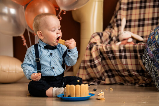 Baby boy celebrating first birthday with a messy cake smash.