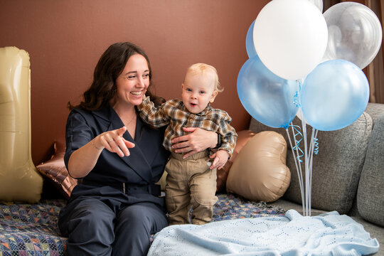 Woman playing with happy child on his first birthday celebration