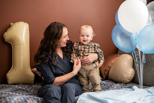 Woman playing with happy child on his first birthday celebration