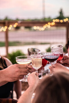Friends raising glasses toasting at outdoor celebration dinner at dusk
