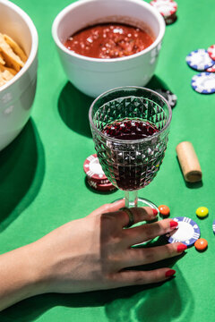 Person enjoying wine with snacks during home poker game