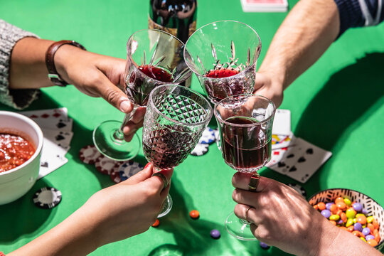 Friends toasting wine while playing poker on green table