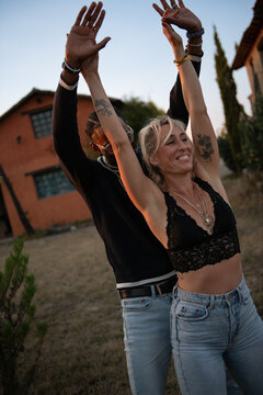 young couple dancing outside with their arms up at dusk