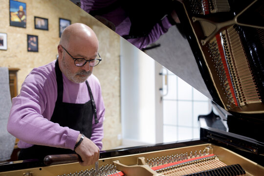 Piano tuner adjusting grand piano strings indoors
