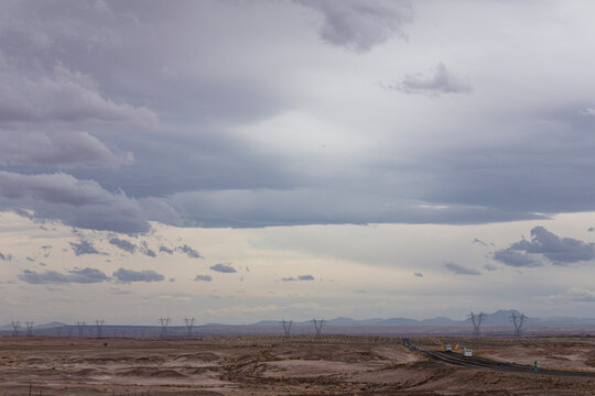 Distant roadway and high voltage utility towers in vast landscape