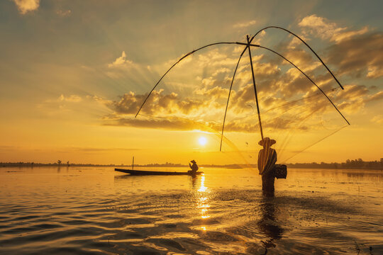 Silhouetted Laguna fisherman casts net at sunset