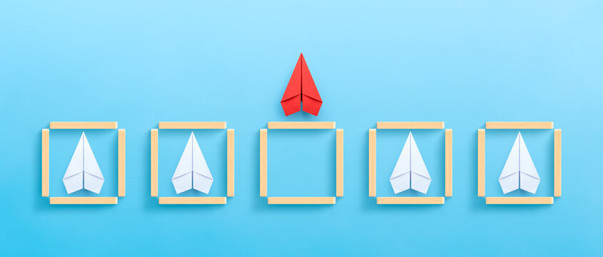 Red paper plane flying out of a box of wooden blocks on blue background. Business concept for new ideas creativity and innovative solution.