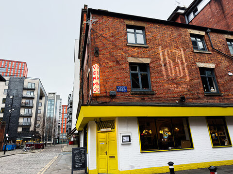 Bright yellow Maricarmen spanish tapas bar on red brick building in Manchester UK street scene