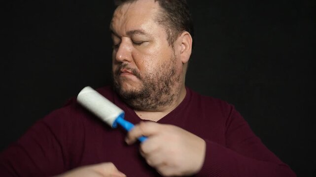 Man cleaning clothes with lint roller at home, closeup