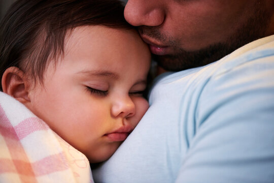 Close-up of father kissing sleeping baby girl