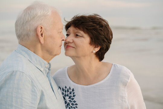Senior couple rubbing noses in front of the sea, Liepaja, Latvia