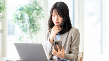 スマートフォンを持ちながら考える女性ビジネスパーソン, Businesswoman thinking while holding smartphone © Trickster*
