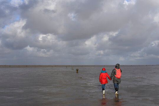 Germany, Lower Saxony, North Sea, Hamburg Wadden Sea National Park, Neuwerk, low tide, mother and daughter walking in mudflat