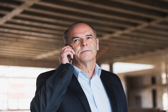 Businessman on cell phone in building under construction