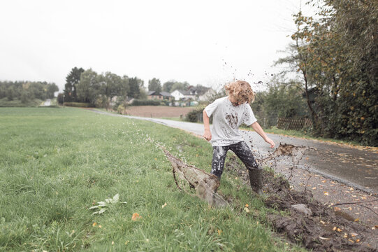Boy jumping into a muddy puddle