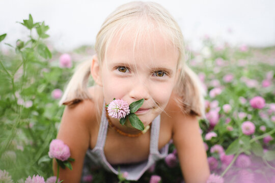 Portrait of smiling girl with clover flower in her mouth