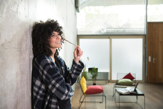 Smiling woman leaning against concrete wall in a loft