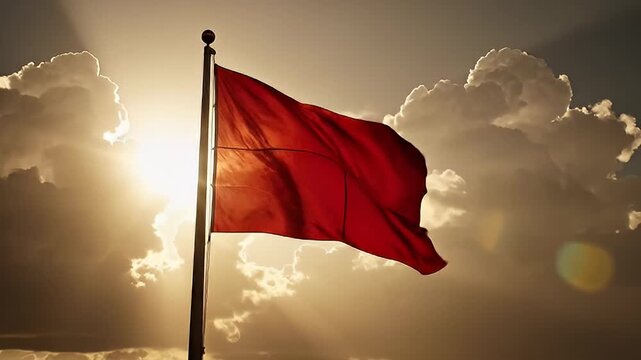 Red flag waving in the wind against a dramatic sunset background