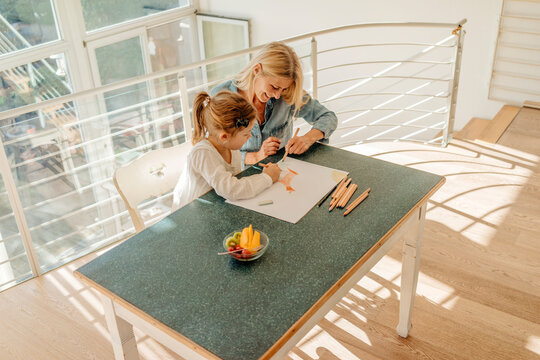 Mature woman and girl at home drawing together