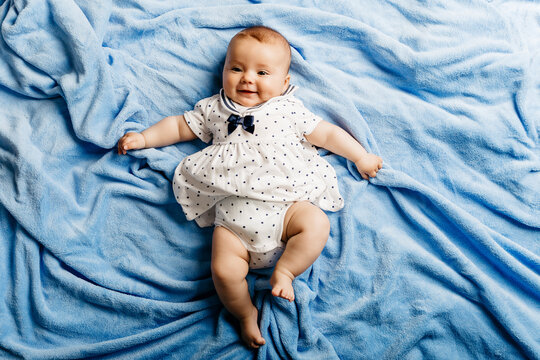 Portrait of smiling baby girl lying on light blue blanket
