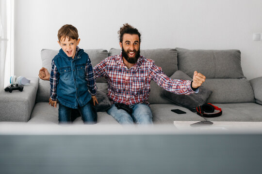 Portrait of father and son playing computer game together on the couch