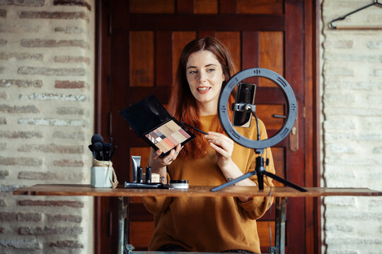 Beautician making make up tutorial on mobile phone while standing at home
