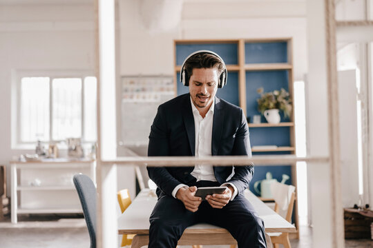 Businessman with tablet and headphones sitting on table