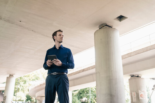 Businessman standing at underpass holding tablet