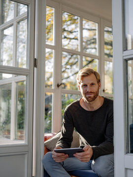 Portrait of man using tablet in sunroom at home