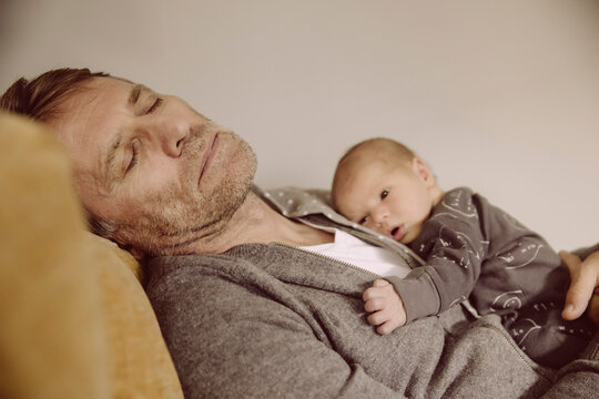 Father taking a nap with newborn awake on his chest