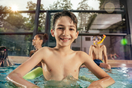 Portrait of smiling boy with friends in indoor swimming pool