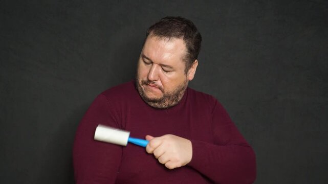 Man cleaning clothes with lint roller at home, closeup