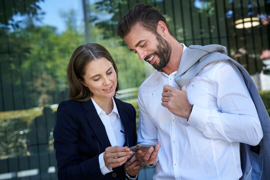 Businessman and businesswoman looking at cell phone in the city