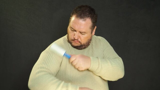 Man cleaning clothes with lint roller at home, closeup