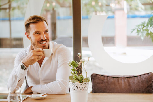 Smiling man with tablet drinking espresso in a cafe