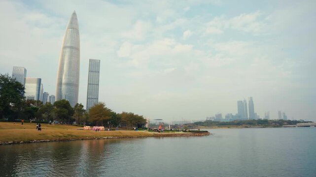 Wide static shot of Shenzhen Bay Cultural Plaza and China Resources Headquarters with Spring Bamboo Tower rising above waterfront park in Nanshan District, showing modern corporate architecture