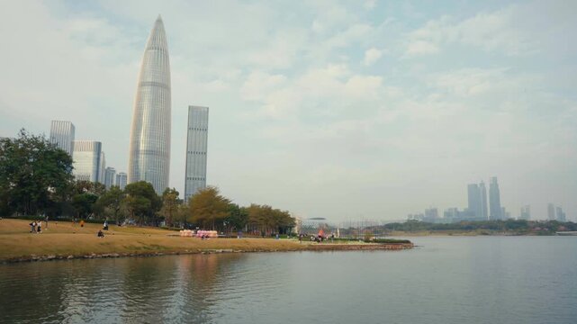 Static wide shot of China Resources Headquarters and Spring Bamboo Tower overlooking Shenzhen Bay Cultural Plaza and waterfront park in Nanshan District, showing modern architecture and calm urban