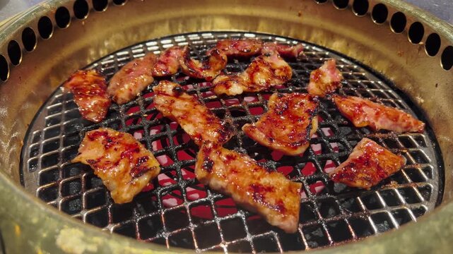 Meat sears over high charcoal flames at a Japanese-style BBQ. Flames flare up as the meat cooks, creating an intense cooking moment.