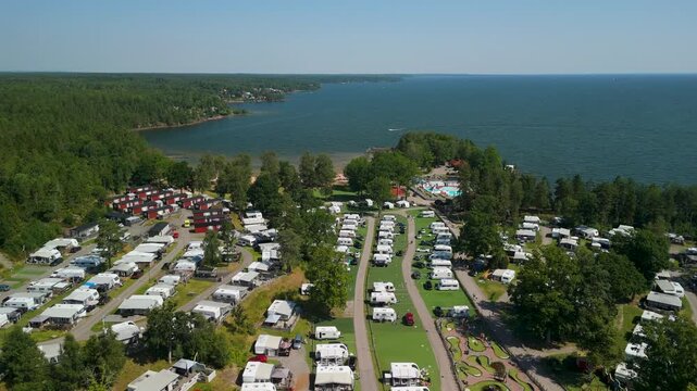 Aerial parallax shot of Ursand Camping and Beach with caravans, fores,t and lake V&auml;nern shoreline on a clear summer day