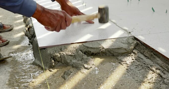This image depicts manual process of laying concrete tiles at a construction site.