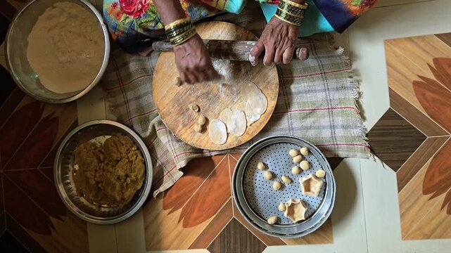 A woman traditionally prepares naivedya (offering) featuring puran poli. The setup shows puran (sweet lentil stuffing) being rolled into thin flatbreads on a wooden board.