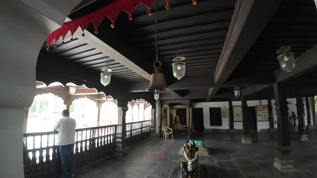 A scenic view of the historic temple backyard area within the Rajwada Palace in Indore, Madhya Pradesh, featuring traditional Maratha architecture with ornate wooden pillars and a sunlit courtyard